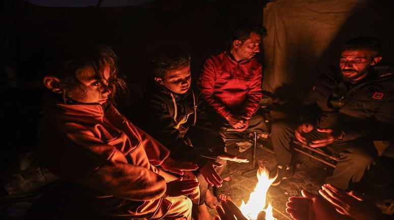 عائلات نازحة تتجمع حول النار للتدفئة في مدينة غزة في ظل الأجواء الباردة